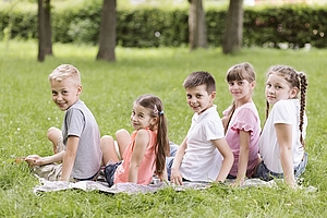 Kinder sitzen in der Wiese